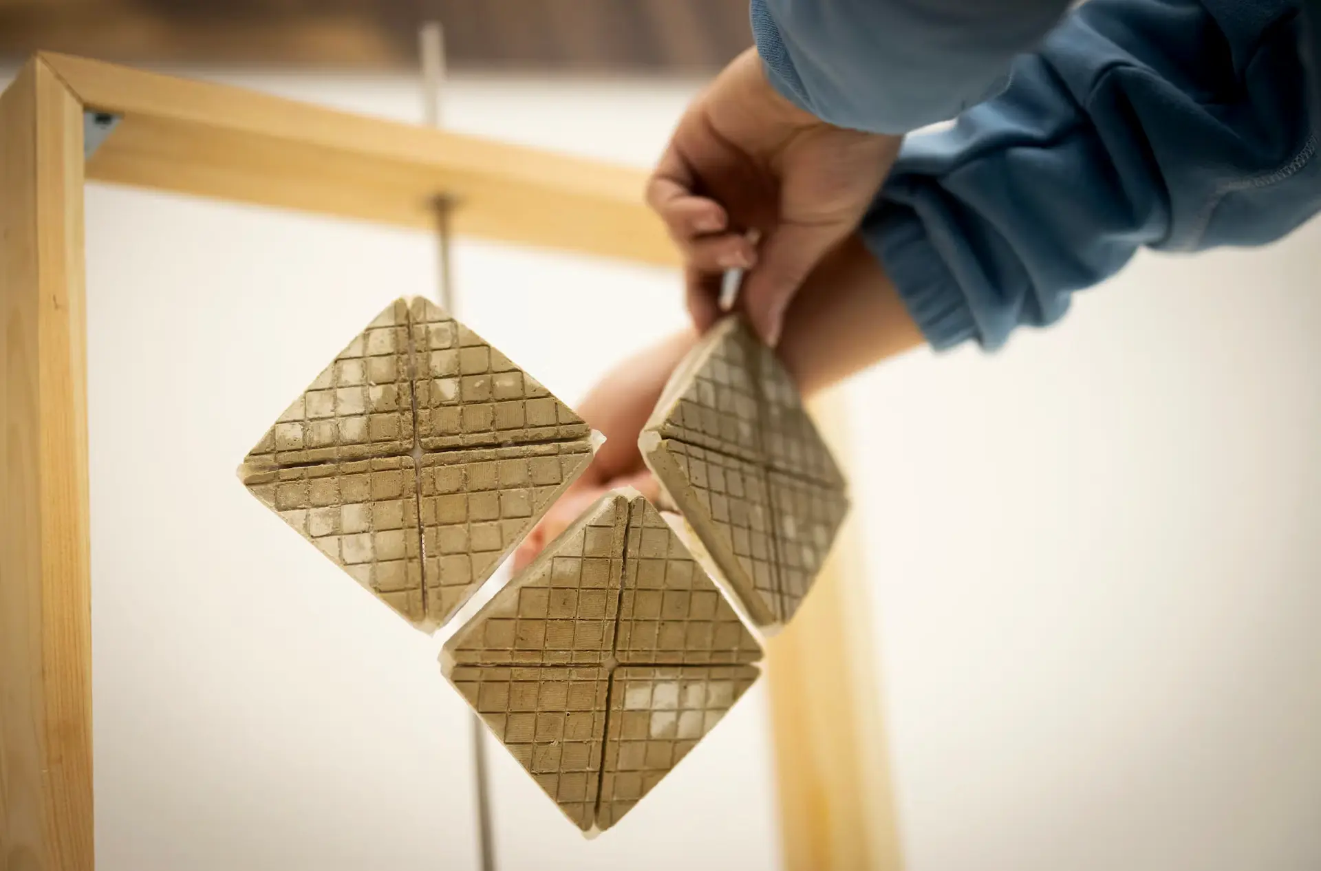 Hands holding diamond-shaped elephant-skin-inspired cement tiles with textured surfaces and engineered cracks, developed by University of Pennsylvania researchers